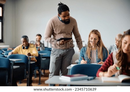 Mid adult woman studying with help of African American teacher during educational class in lecture hall. Royalty-Free Stock Photo #2345710639