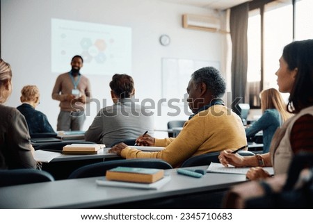 African American senior man taking notes during education training class.  Royalty-Free Stock Photo #2345710683