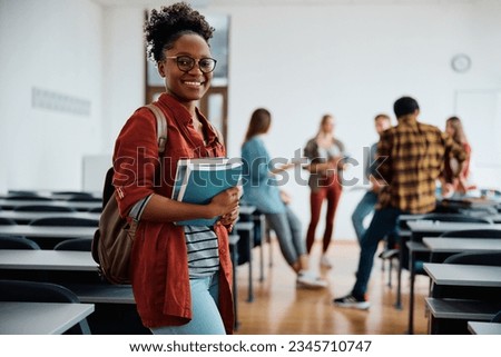 Young happy woman at university classroom looking at camera.