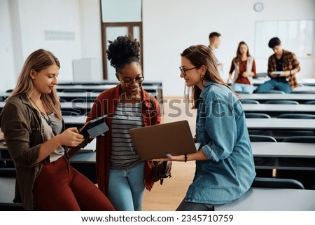 Multiracial group of female students using wireless technology in university classroom. 