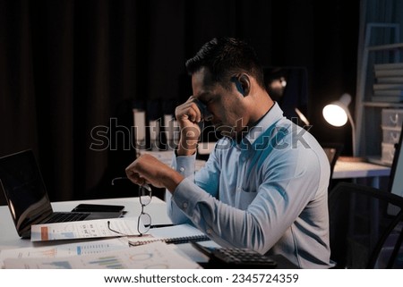 Tired and exhausted young Asian businessman feeling upset and tired after working too much, working over night alone in his office room. Royalty-Free Stock Photo #2345724359