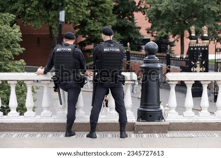 Russian police officers patrol a city street in Moscow on Kremlin background. Translation of inscription on the human backs: "Ministry of Internal Affairs of Russia"
