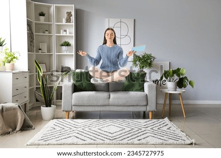 Flying young woman with book over sofa at home Royalty-Free Stock Photo #2345727975