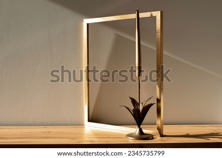Golden decoration in home, golden picture frame with golden decor candlestick during golden hour mock-up. Minimal art in home interior.