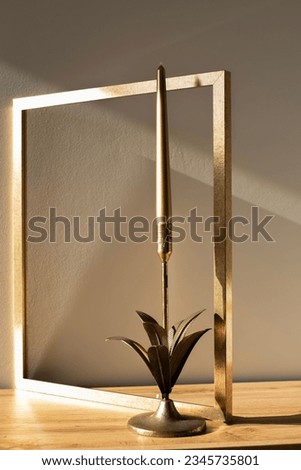 Golden decoration in home, golden picture frame with golden decor candlestick during golden hour mock-up. Minimal art in home interior.