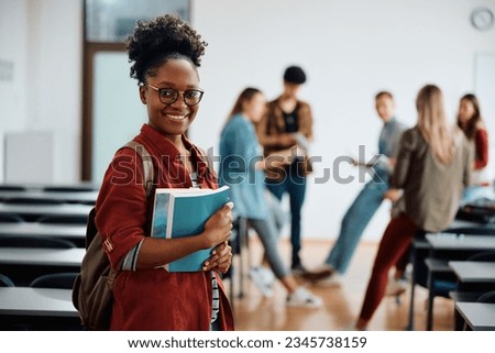 African American college student in lecture hall looking at camera. Her friends are in the background. 