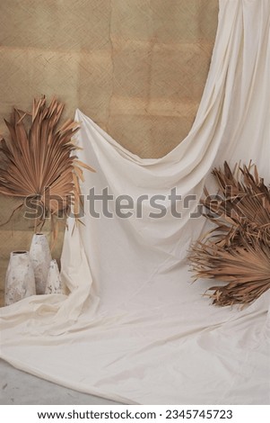 Bohemian ethnic themed photo studio backdrop decoration. Woven matt combined with neutral cloth, potteries and dry palm leaves