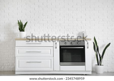 Interior of modern kitchen with white counters, oven, clean dishes and houseplants Royalty-Free Stock Photo #2345748959