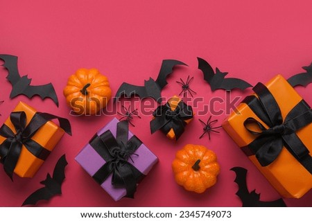 Composition with gift boxes, pumpkins and paper bats for Halloween on purple background