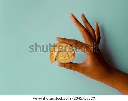 Young asian women holding mini vanilla roll cake, swiss roll cake or sponge roll with Vanilla flavor. Thai call Jam Rolls. isolated on blue background Royalty-Free Stock Photo #2345759999