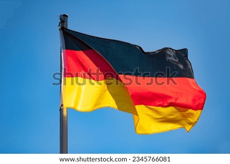 German flag in black-red-gold color on a sunny day in Germany. National yymbol of the “Bundesrepublik Deutschland“. Flag pole and wavy fabric blown in the wind on a blue sky day. Intense sunlit colors Royalty-Free Stock Photo #2345766081