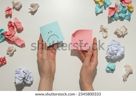 Hands holding paper with happy and angry face, bipolar disorder concept