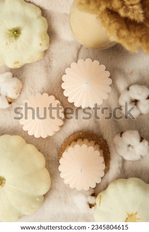 Candles and zucchini on beige background, top view