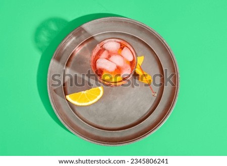Plate with glass of tasty Negroni cocktail on green background