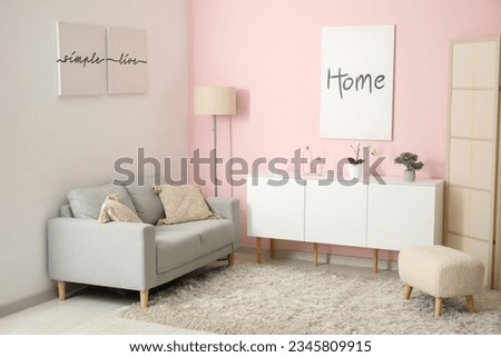 Interior of living room with cozy grey sofa, white cabinet and posters