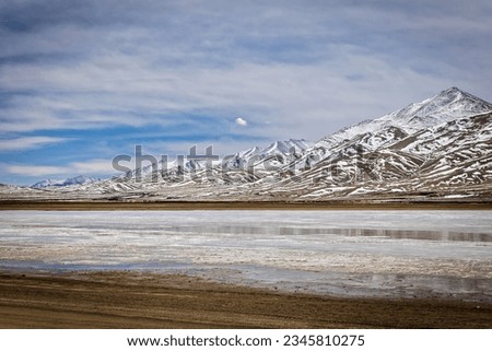 Snow bands beautifully trace the peaks of the brown mountain range as they create a distinctive desert palette in Ladakh. Winter picture in the frigid deserts offers a mix of tranquility and despair.