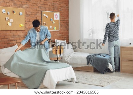 Male students tidying up in dorm room Royalty-Free Stock Photo #2345816505