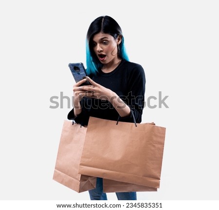Girl with colored blue hair with shopping bags in her hand using phone. Young girl using phone after shopping. Translation: Aurat means "Women" - Ladki means "girl" - Baaghi means "rebel" 