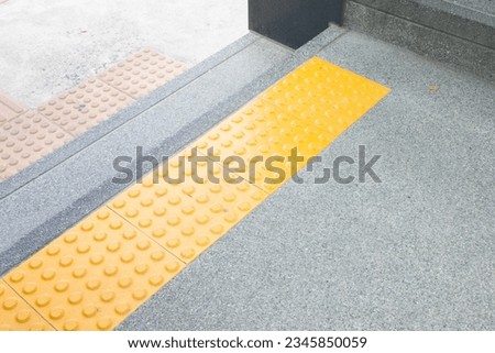 Bright yellow tactile paving for blind pedestrians on street or sidewalk,Guiding block for disability.