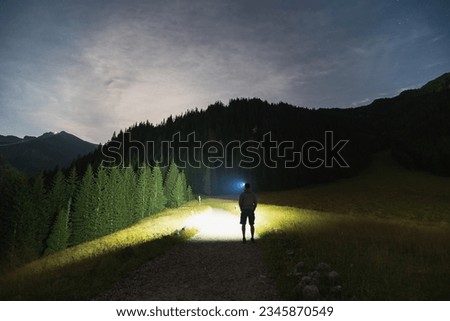 Night scene, the silhouette of a man with a headlamp goes hiking in the Tatra Mountains in summer. High quality photo