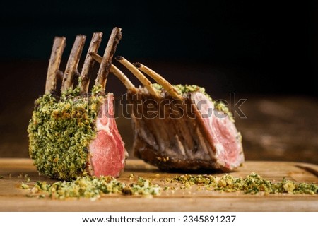 Rack of lamb with hazelnut herb crust on wooden board in restaurant Royalty-Free Stock Photo #2345891237