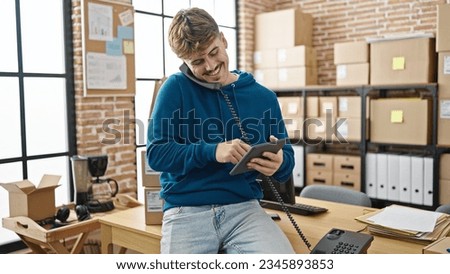 Young hispanic man ecommerce business worker using touchpad talking on telephone at office
