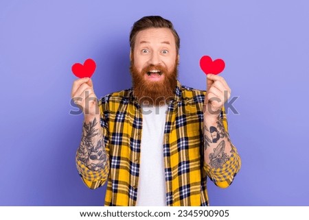 Portrait of astonished positive person hands hold small red paper heart shape cards isolated on purple color background
