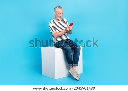 Full length photo of stylish man user sit platform reading post answer sms typing texting letter isolated on blue color background