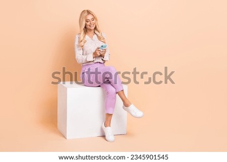 Photo of cheerful wear trendy clothes sit podium hold modern gadget read facebook instagram empty space isolated on beige color background