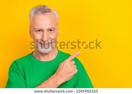 Photo of good mood cheerful man wear green t-shirt showing finger empty space isolated yellow color background