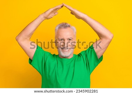 Photo of cheerful positive guy dressed green t-shirt showing arms roof isolated yellow color background