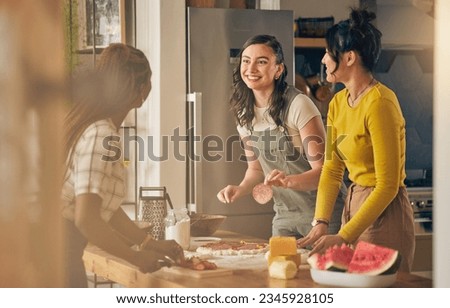 Happy, friends and women cooking pizza in kitchen, bonding and having fun together in home. Smile, girls and baking food, margherita and salami bread at lunch, cheese on meat and watermelon at brunch Royalty-Free Stock Photo #2345928105