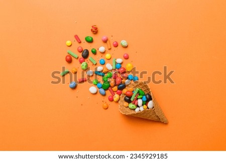 waffle cone full of assorted traditional candies falling out on colored background with copy space. Happy Holidays sale concept.