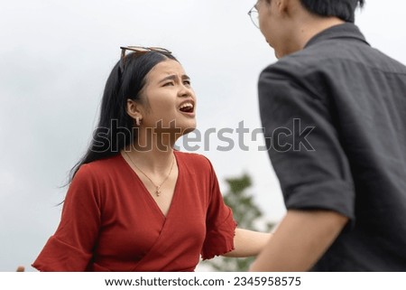A young asian couple having a heated and vocal conversation outside a public area. A tense and toxic relationship between two assertive and unyielding people in a bitter power struggle. Royalty-Free Stock Photo #2345958575