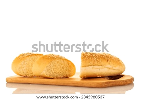One fragrant bun cut into slices sprinkled with sesame seeds on a wooden board, close-up, isolated on white.

