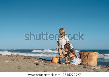 a little boy and a girl of three years old play in the sand on t