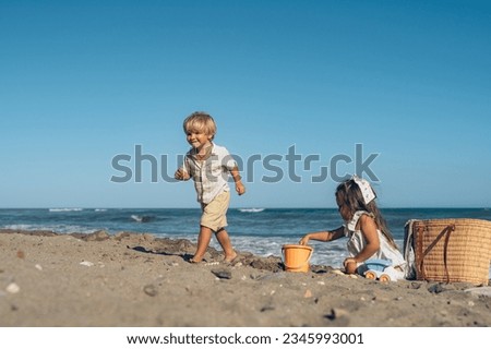 a little boy and a girl of three years old play in the sand on t