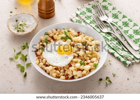 Potato hash with pancetta topped with a fried egg and fresh herbs Royalty-Free Stock Photo #2346005637