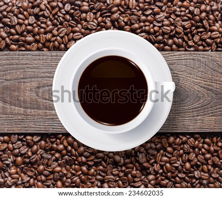 Cup of coffee and coffee beans with wooden texture background.