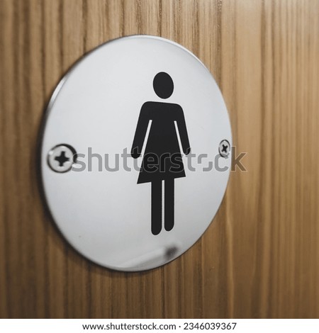 Close up of stainless steel symbol indicating the entrance to female toilets