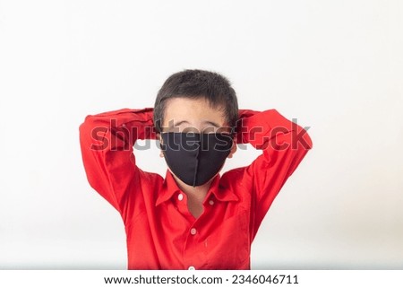 Cute boy in red shirt wearing black mask Cheerful appearance sitting in a white room
taken in the studio.
Studio portrait, concept health with white background. 