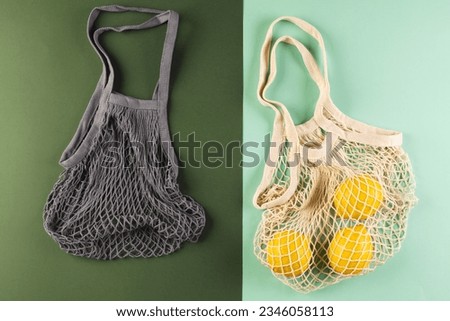 Brown and white mesh net bags with lemons and copy space on light and dark green background. Shopping, bag, colour, fabric, texture and materials concept.