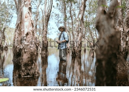 Asian man traveling hiking taking photos alone in the Asian mangrove forests.