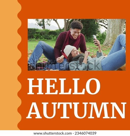 Composite of hello autumn text over happy diverse couple having picnic in autumn park. Autumn, fall and seasons concept digitally generated image.