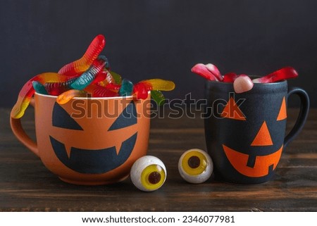Jelly candy worms, Halloween cup on dark background. Halloween decorations and sweets.