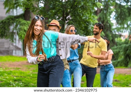 Group of multiethnic friends at birthday party in the city park dancing, summer fun doing the conga