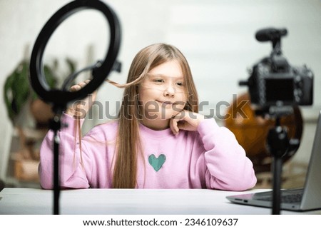 A beautiful blonde teenager is broadcasting live. The video blogger has a live broadcast. An annular lamp and a camera during a live broadcast of a video blogger.