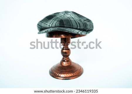 Studio photo concept for classic eight-panel newsboy cap with wool material. newsboy hat in black and white with a tartan pattern mounted on a bronze mannequin head on a white background. Royalty-Free Stock Photo #2346119335