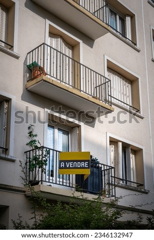 'A vendre' (English translation: 'For sale') written in French on a yellow sign fixed to the exterior of an apartment in a residential building. Concept of housing real estate market in France
