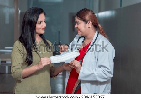 Indian female doctor or gynecologist advice to woman use sanitary pads at hospital
